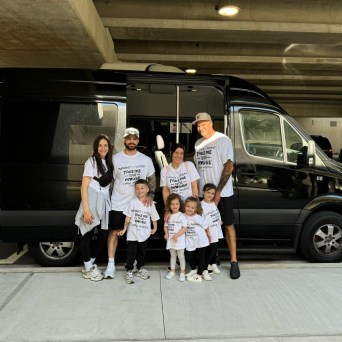 Family of seven in matching outfits standing by a black van.