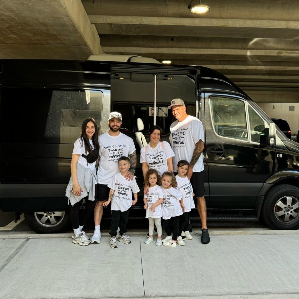 Family of seven in matching outfits standing by a black van.