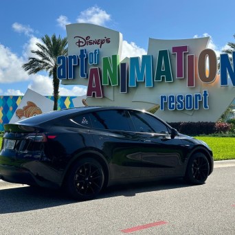 Black car parked in front of Disney's Art of Animation Resort sign.